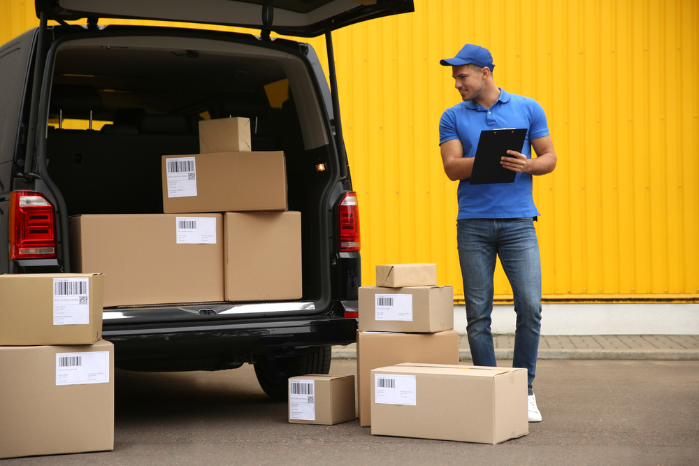man with clip board and packages in van